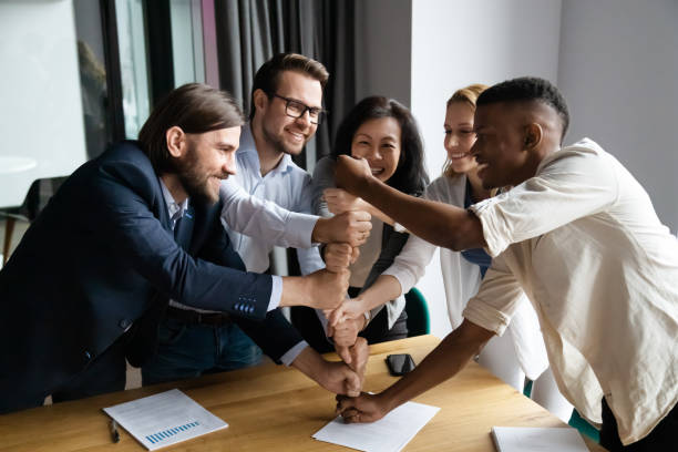 istock Overjoyed multiethnic businesspeople stack fists engaged in teambuilding 1265084569