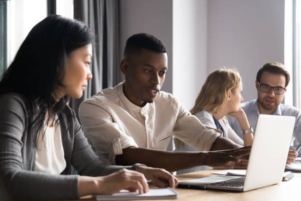 istock Serious diverse colleagues brainstorm working on laptop in office 1265084580