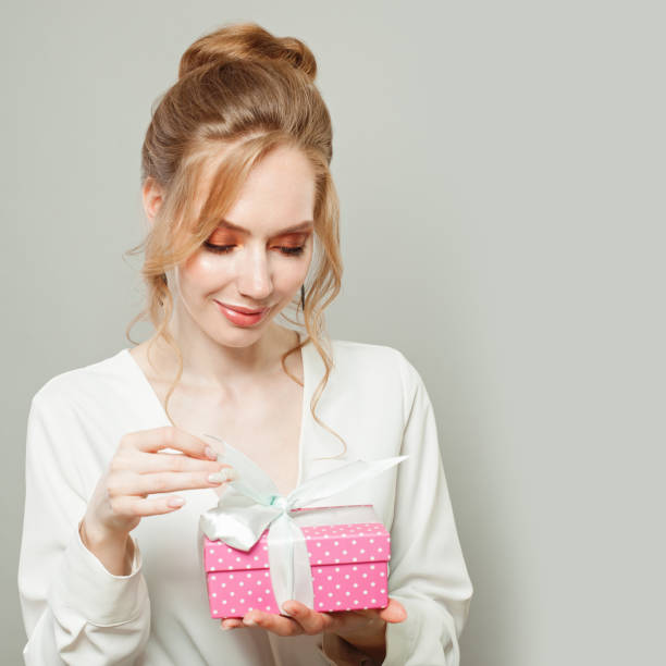 istock Cheerful young woman with pink gift box on white background 1265084776