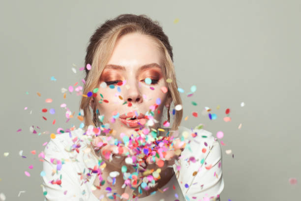 istock Beautiful woman blowing colorful confetti 1265084779