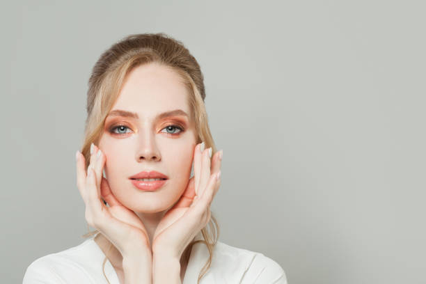 Pretty young woman face with clear healthy skin, makeup and manicured nails on hands close up portrait Pretty young woman face with clear healthy skin, makeup and manicured nails on hands close up portrait Best Face Serums stock pictures, royalty-free photos & images