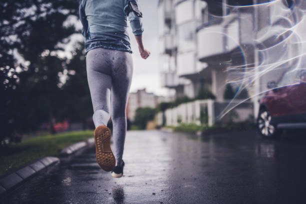 Unrecognisable athlete jogging at rainy day.