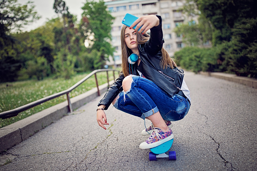 Teenage girl is taking selfie/making video call on her skateboard