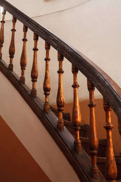 istock wooden spiral staircase railing with selective focus. Old house interior vertical shot 1265089120