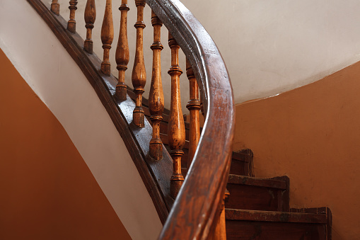 Old wooden spiral staircase railing with selective focus