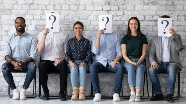 candidati diversi sorridenti seduti in fila con persone sconosciute - african descent question mark holding asking foto e immagini stock