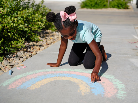 Girls enjoying on sunny day in the public park and drawing with chalks