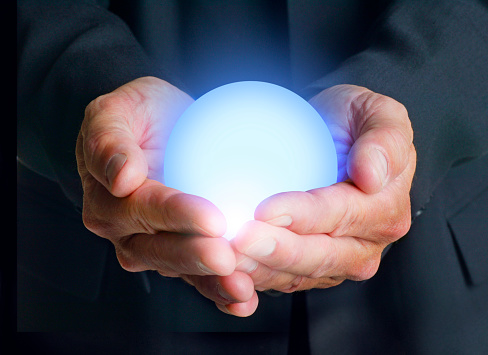 A businessman holds a glowing orb in his hands.