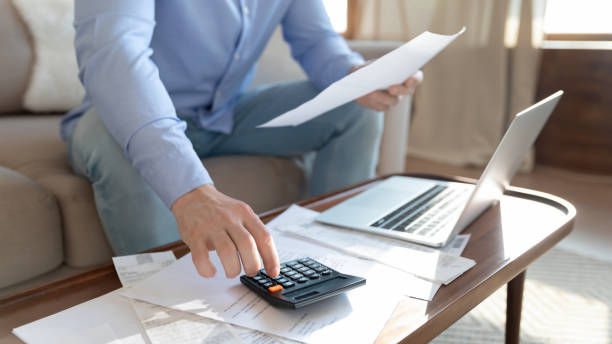 istock Young man calculating monthly household expenditures alone at home. 1265099392
