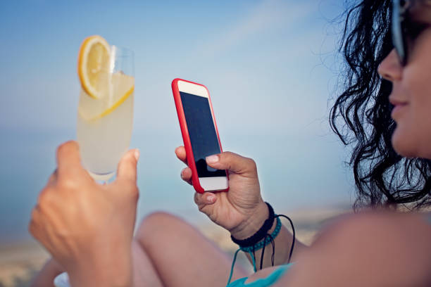 istock Woman is drinking her cocktail and texting on the beach 1265099538