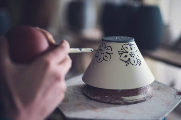 The hands of the female artist decorated ceramic bowl.