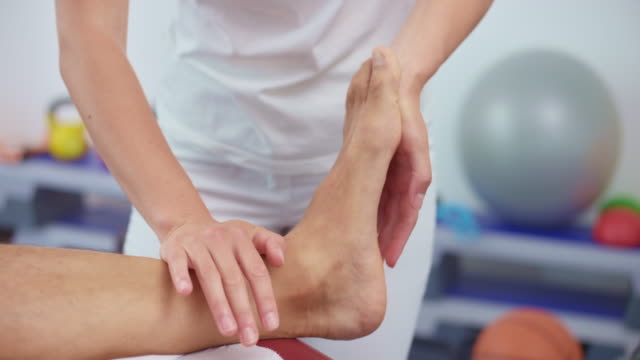 SLO MO Hands of a female sport therapist massaging a problematic ankle