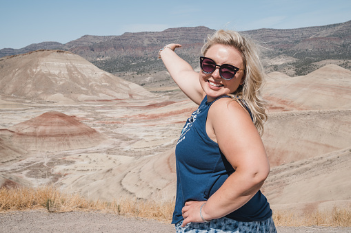Beautiful blonde woman in casual clothing poses at the Painted Hills overlook at the John Day Fossil Beds National Monument