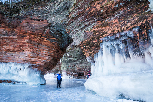 Woman walks through sandstone arch while visiting the ice caves at Apostle Island National Lakeshore, Cornucopia, Bayfield County, Wisconsin, USA