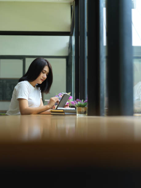 istock Female university student doing homework with digital tablet on table in cafe 1265114923