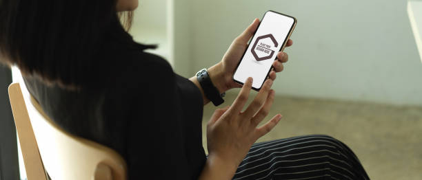 istock Female using mock up smartphone while relaxed sitting on chair near glass window 1265114978