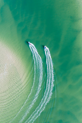 Small boats create a wake as they move along the clear green waters of the Noosa river