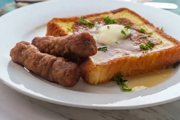 Classic American breakfast french toast with maple syrup served with side of sausage links