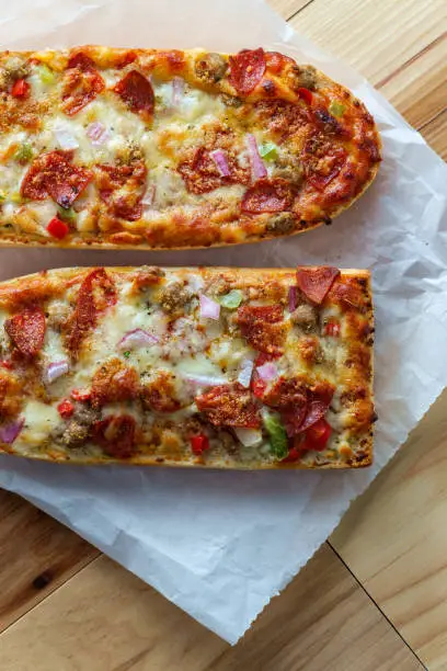 Supreme French bread pizza with pepperoni sausage black olives red onion and green bell pepper toppings