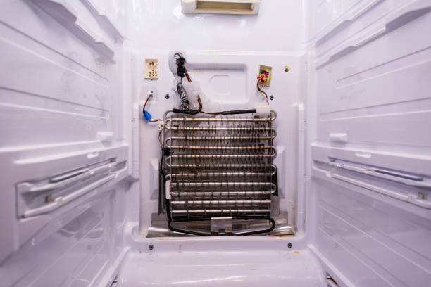 Refrigerator repair. Freezer compartment back panel removed. Evaporator coils with a frozen thermostat Refrigerator repair. Freezer compartment back panel removed. Evaporator coils with a frozen thermostat. fridge coils stock pictures, royalty-free photos & images