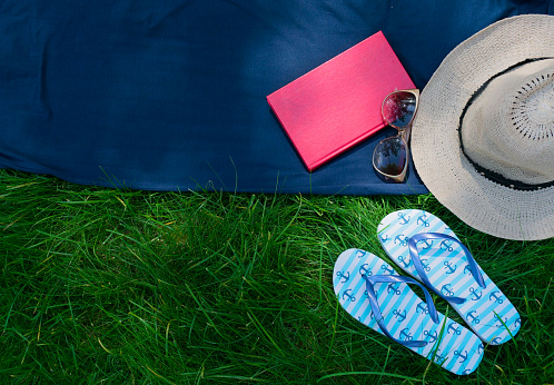 Hat, sunglasses, flip flops on the  green grass. Summer vacation concept. Copy space.