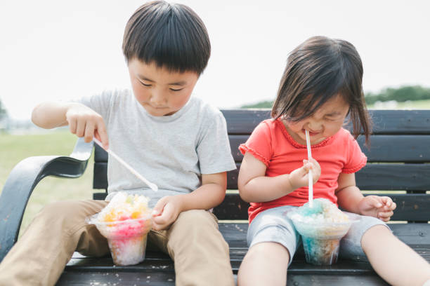 istock Sibling eating shaved ice in the park 1265133814