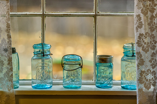 Still life at a lost place. Ancient glass bottles of various sizes on a shelf in an abandoned wooden shed.