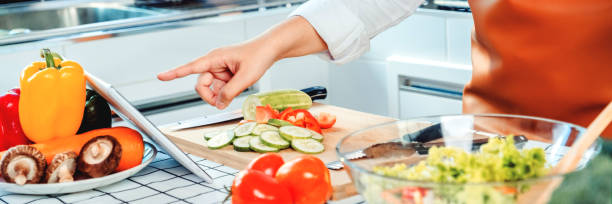 istock Vegetarian young woman using a digital tablet to study how to cooking vegetable salad in kitchen 1265143179