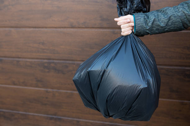 istock The guy holds a black trash bag close-up 1265143324