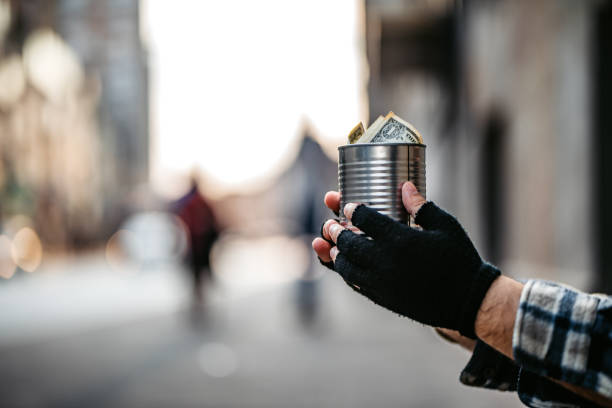 Beggar holding a can for money Beggar holding a can for money on city street, close up. beggar stock pictures, royalty-free photos & images