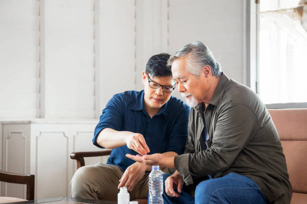 fils d’âge moyen prend soin du père aîné malade, concepts de famille asiatique de bonheur - senior adult child holding grandparent photos et images de collection