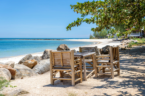 Bamboo table and chairs on tropical sand beach near blue sea water on the island Koh Phangan, Thailand