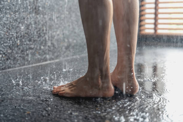 Legs of the girl standing under the shower under the stream of water, health beauty and hygiene concept stock photo