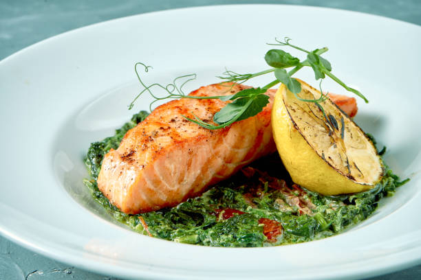 istock Grilled salmon steak with stewed spinach in white plate on concrete background 1265151792