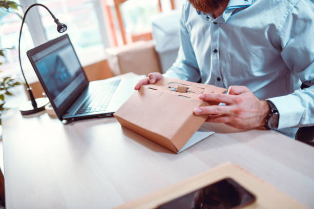 male office worker folding a cardboard package - packaging design imagens e fotografias de stock