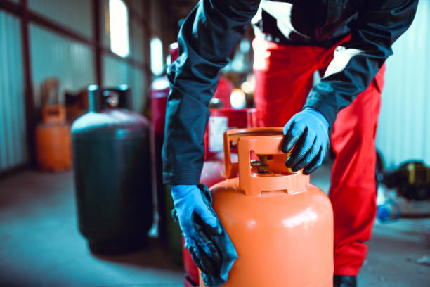 worker cleaning liquefied gas cylinder - botija de gas imagens e fotografias de stock