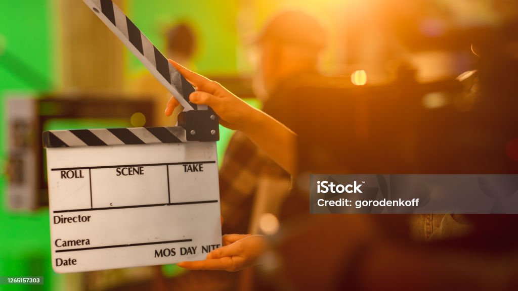 Close up Shot On Film Studio Set Young Camera Assistant Holds Empty Clapperboard. In the Background Director Shooting Green Screen Scene. History Costume Drama Movie. Movie Stock Photo