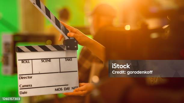Close Up Shot On Film Studio Set Young Camera Assistant Holds Empty Clapperboard In The Background Director Shooting Green Screen Scene History Costume Drama Movie Stock Photo - Download Image Now