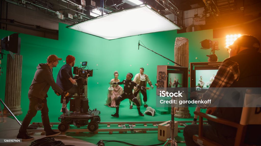 On Big Film Studio Professional Crew Shooting Period Costume Drama Movie. On Set: Directing Green Screen Scene with Gentleman Protecting Lady from Actor Playing Monster Wearing Motion Capture Suit Movie Stock Photo On Big Film Studio Professional Crew Shooting Period Costume Drama Movie. On Set: Directing Green Screen Scene with Gentleman Protecting Lady from Actor Playing Monster Wearing Motion Capture Suit Movie Stock Photo
