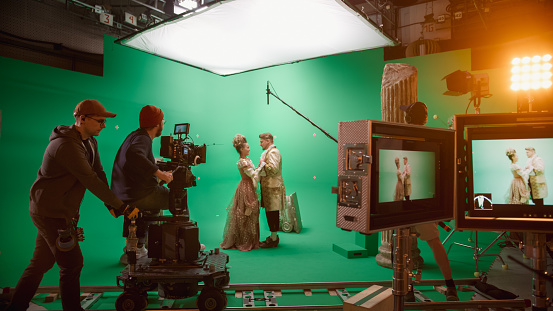 On Set: Famous Female Director Controls Cameraman Shooting Green Screen Scene with Two Actors Talented Wearing Renaissance Clothes Talking. Crew Shooting Period Costume Drama Movie.
