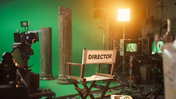 Photo of Film Studio Set with Focus on Empty Director's Chair. On the Studio Film Set with High End Equipment Professional Crew Shooting High Budget Movie