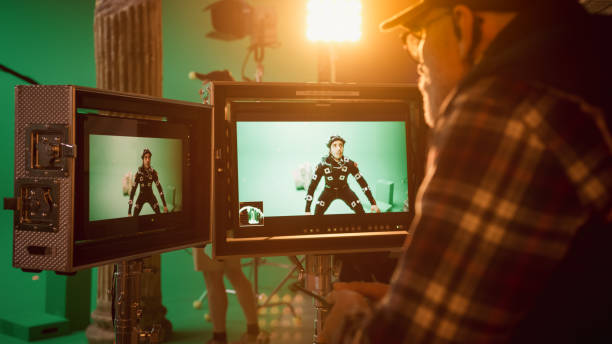 istock Director Looks at Displays Directs Green Screen CGI Scene with Actor Wearing Motion Tracking Suit and Head Rig. In the Big Film Studio Professional Crew Shooting Blockbuster Movie 1265157452