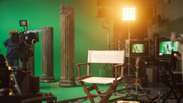 istock Film Studio Set with Focus on Empty Director's Chair. On the Studio Film Set with High End Equipment Professional Crew Shooting High Budget Movie 1265157457