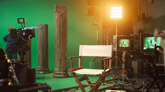 Film Studio Set with Focus on Empty Director's Chair. On the Studio Film Set with High End Equipment Professional Crew Shooting High Budget Movie