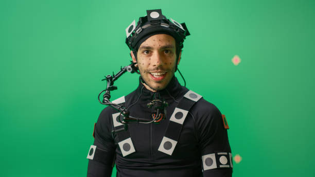 Portrait of an Actor Wearing Motion Caption Suit and Head Rig Posing with Green Screen Background. Big Budget Filmmaking On Film Studio Set Shooting Blockbuster Movie with Chroma Key. Portrait of an Actor Wearing Motion Caption Suit and Head Rig Posing with Green Screen Background. Big Budget Filmmaking On Film Studio Set Shooting Blockbuster Movie with Chroma Key. behind the scenes photos stock pictures, royalty-free photos & images
