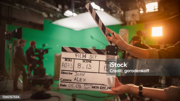 On Film Studio Set Camera Assistant Holds Clapperboard Green Screen Scene With Talented Cameraman In The Background Closeup Shot Stock Photo - Download Image Now