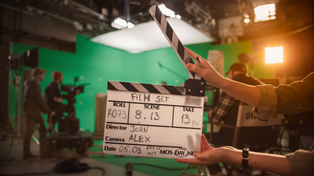 on film studio set camera assistant holds clapperboard. green screen scene with talented cameraman in the background. close-up shot. - dirigindo imagens e fotografias de stock