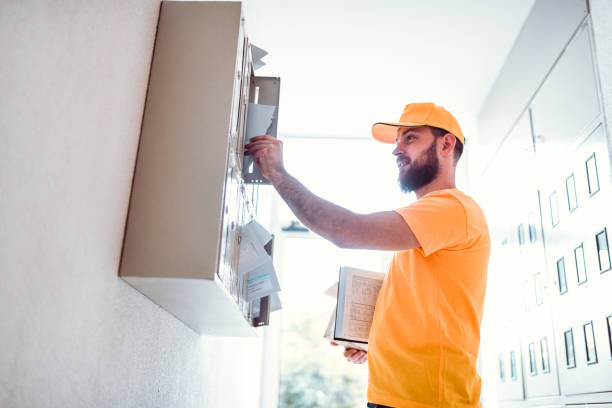Handsome Delivery Man Putting Letters In Right Mailbox