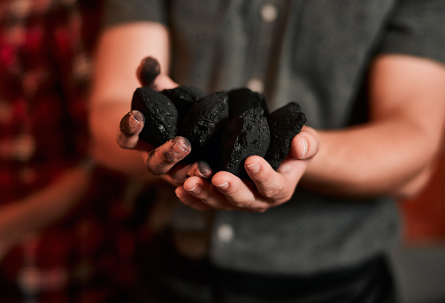 Closeup shot of an unrecognisable man holding a pile of charcoal