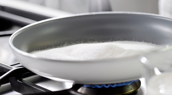 Close up scene of making dessert in a cooking pan with white sugar